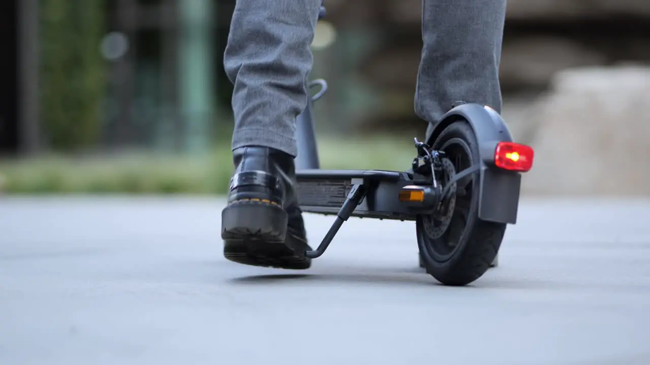 Close up of a businessman getting on an e-scooter and driving away