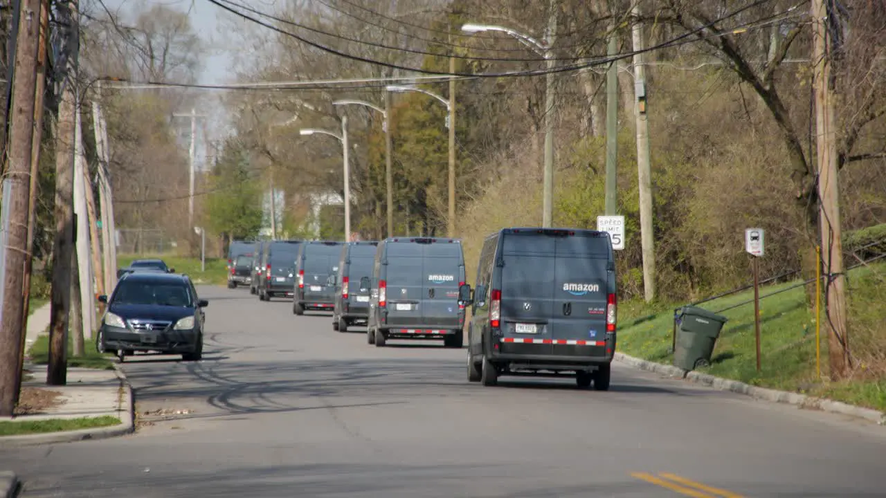 Amazon vans or Amazon trucks pull on a city street