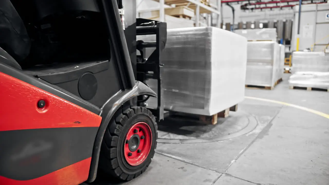 Forklift carrying a wrapped pallet inside of a warehous