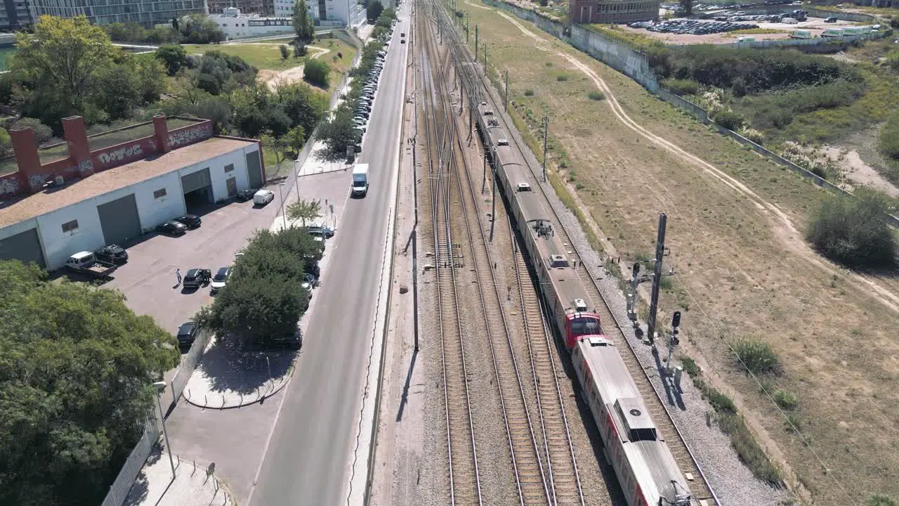 Suburban Passenger Train Moving in a Railway next to a road in Urban Area Lisbon