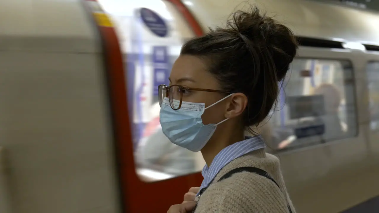 Woman in face mask waiting for tube train in underground station