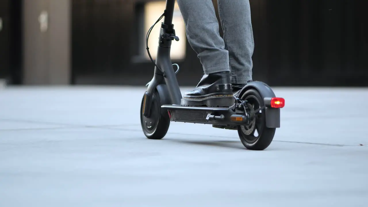 A young businessman drives his e-scooter through the city close up