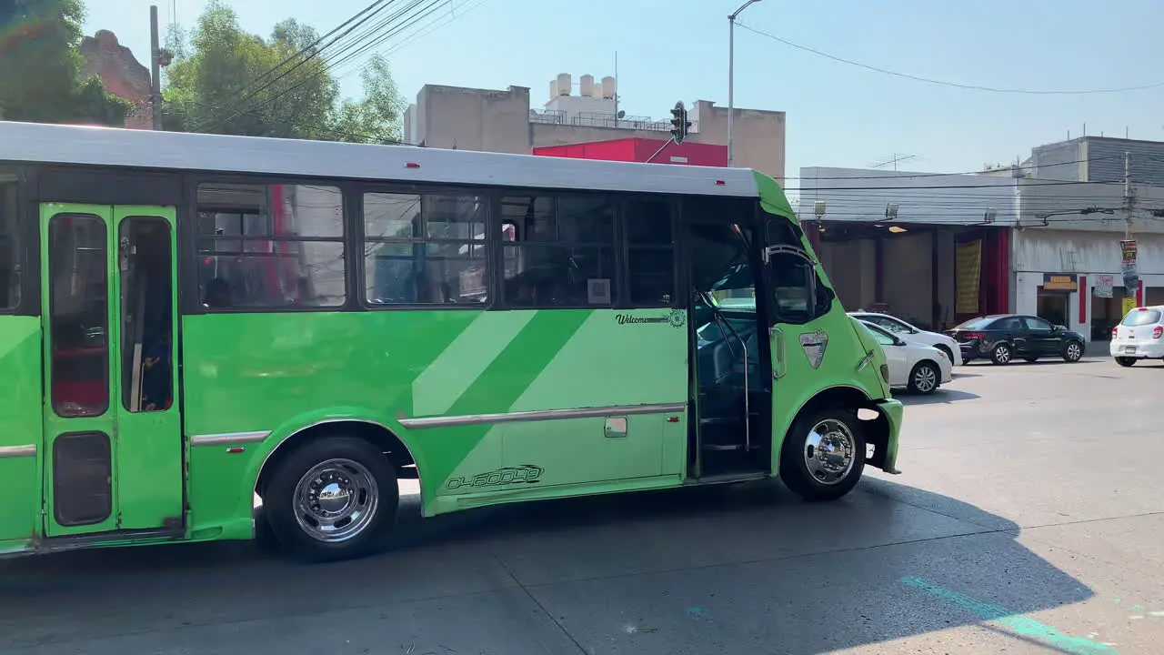 Green Coloured La Buseta Bus Travelling Along Busy Road In Mexico City