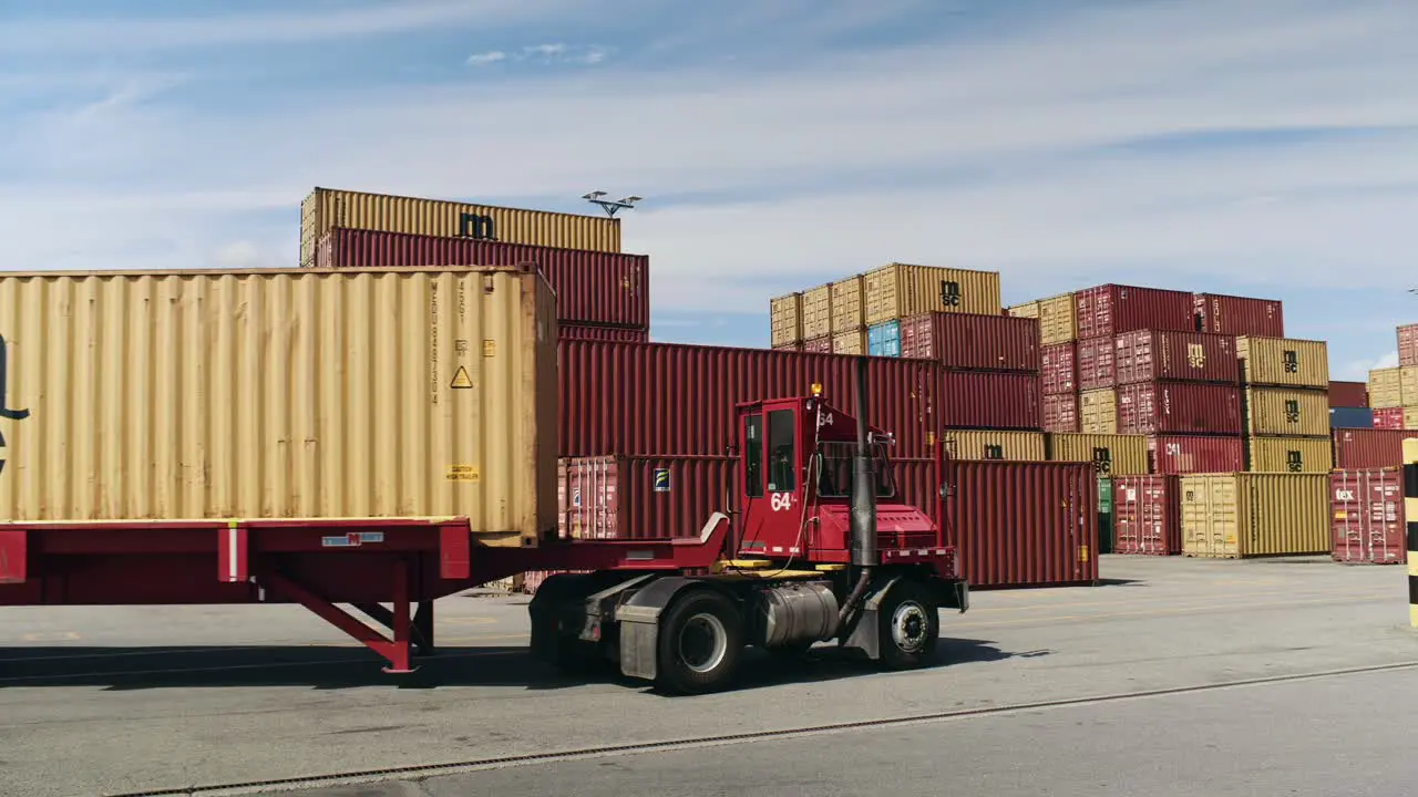 Haulage truck carrying shipping container in Port of Montreal dockyard passing cargo shipment