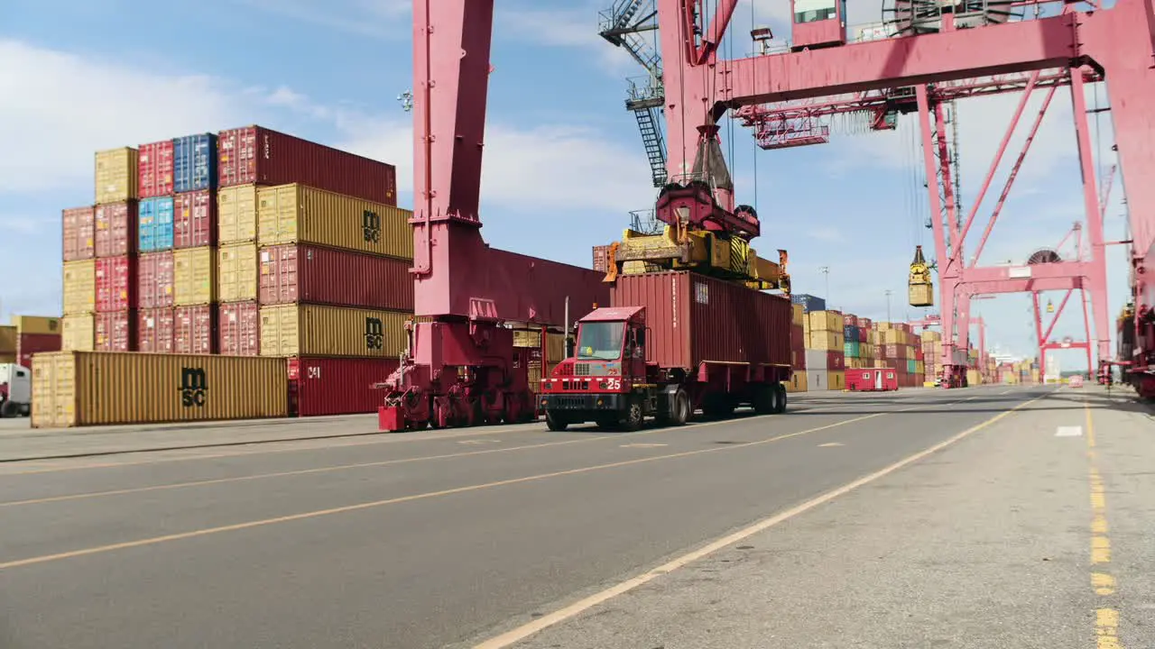 Port of Montreal crane loading storage container onto trailer truck for haulage