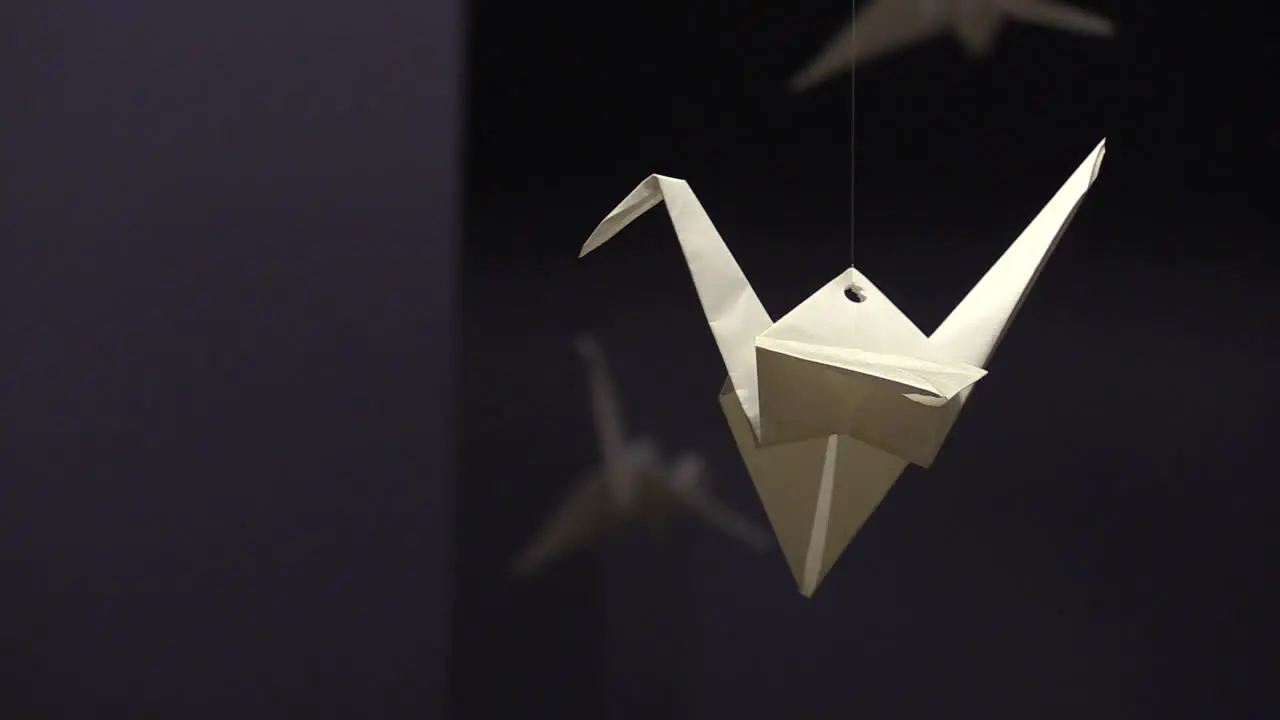 White Paper Origami Crane Hanging In a Dark Room