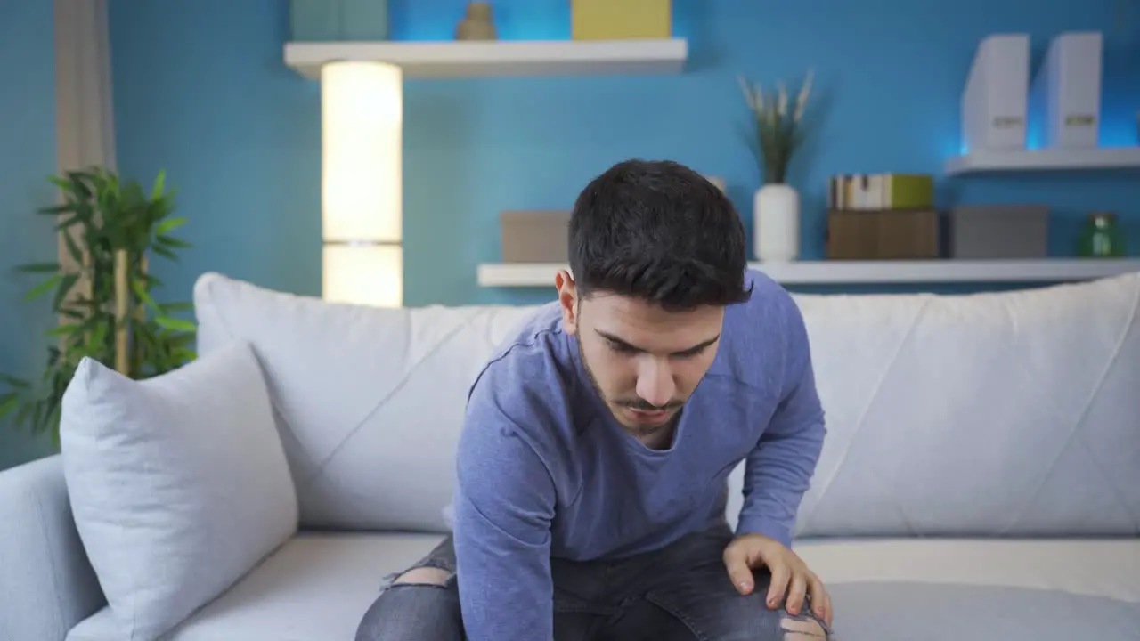 Young man watching horror movie on smartphone alone at home