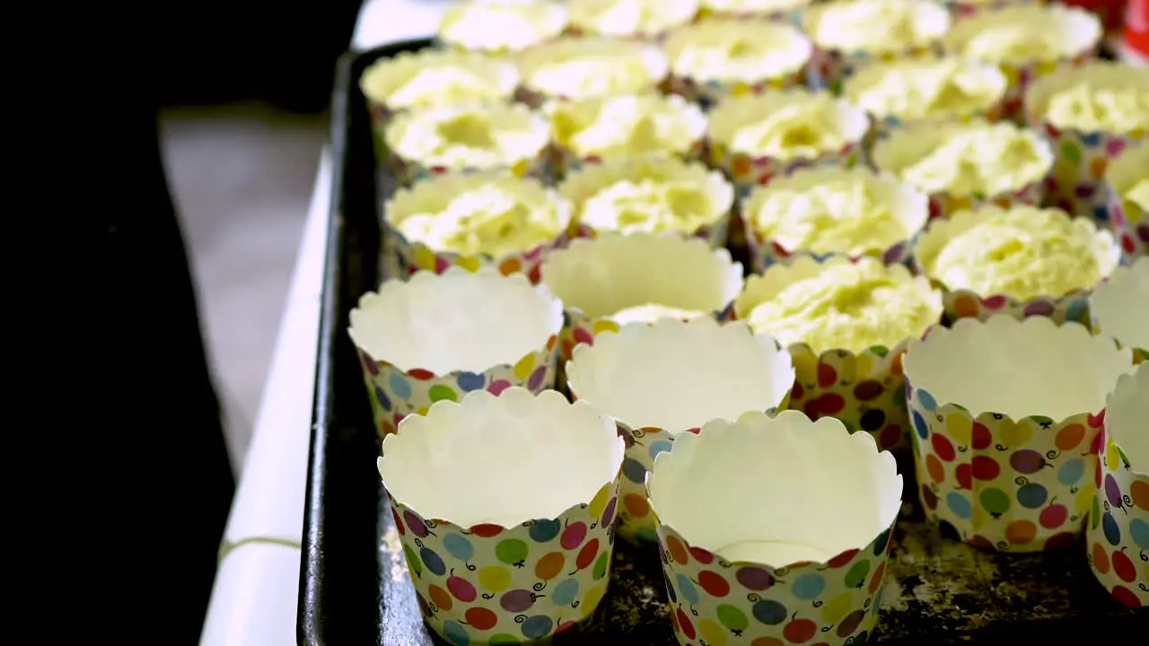 Home cook using an ice cream spoon to fill muffin pans with batter