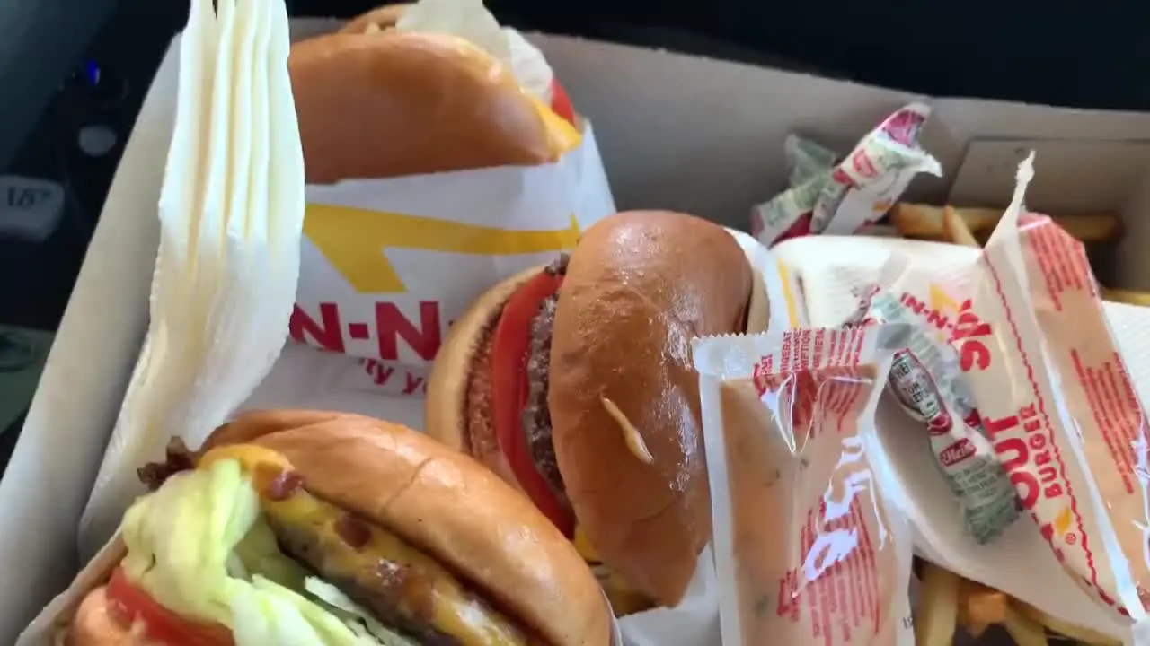 Man picking up food from his car at an IN-N-OUT burger fast food restaurant