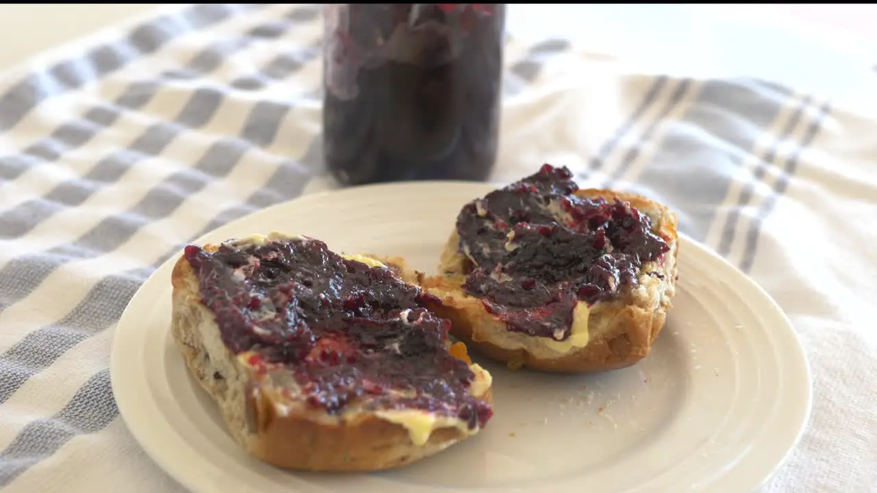 Slow motion pan around hot cross buns with jam and butter sitting on a plate at Easter