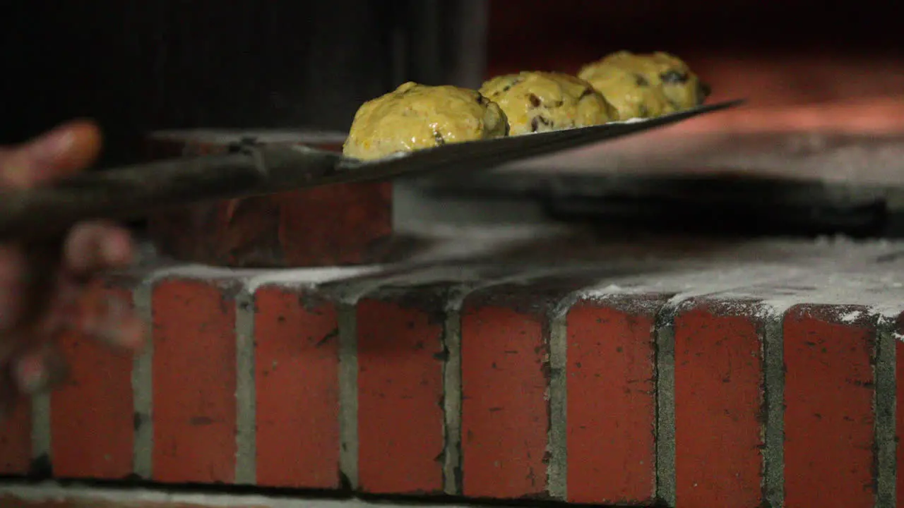 Baker Putting Raisin Bread Dough Brushed With Egg Wash On A Baking Peel close up