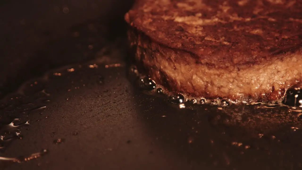 Single Vegan PlantBased Burger Cooking and Sizzling in Hot Pan with Oil Bubbling