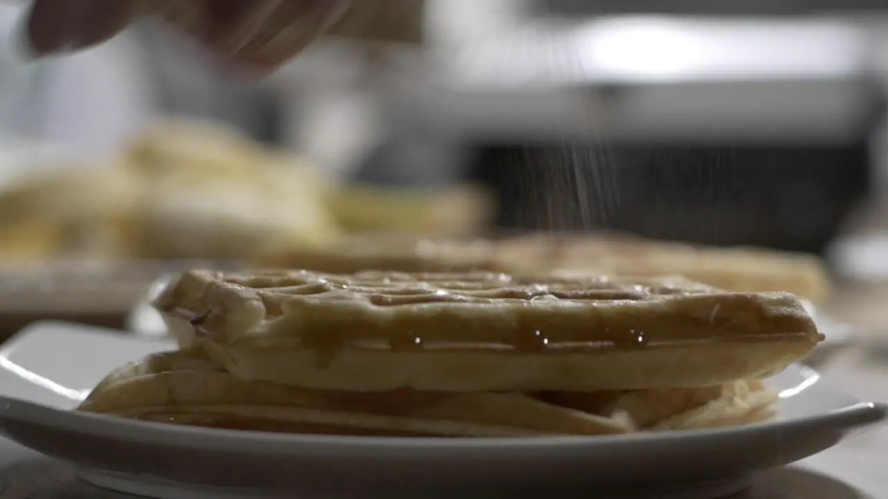 Sprinkling Cinnamon On Top Of Freshly Cooked Waffles In Plate close up selective focus