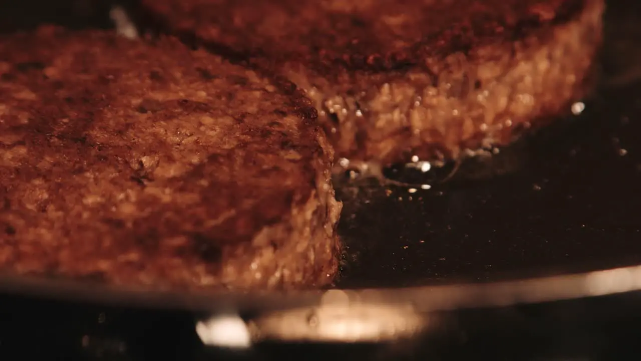 Close Up of PlantBased Imitation Burgers Frying in Hot Pan with Camera Pulling Focus