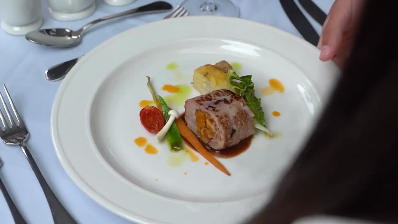 A gourmet dish is being served at a fancy dining table