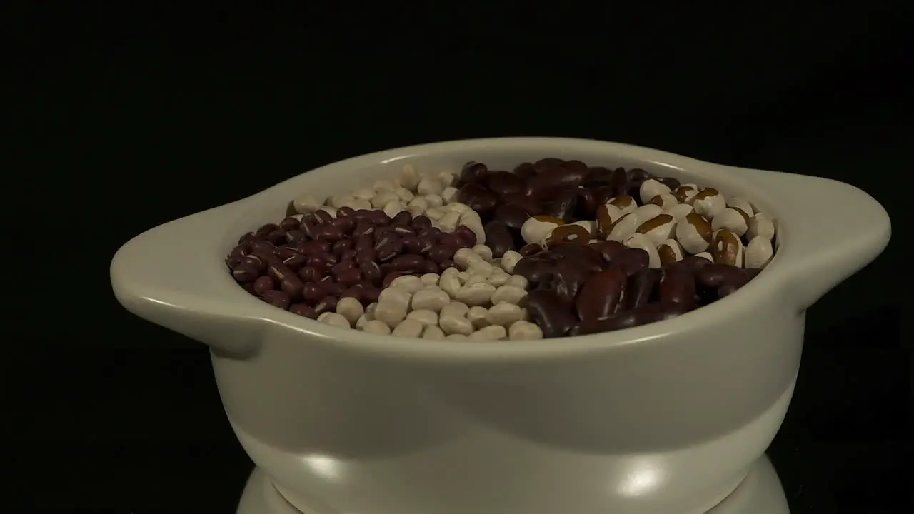 Bowl of dry beans revolves isolated on black background copy space