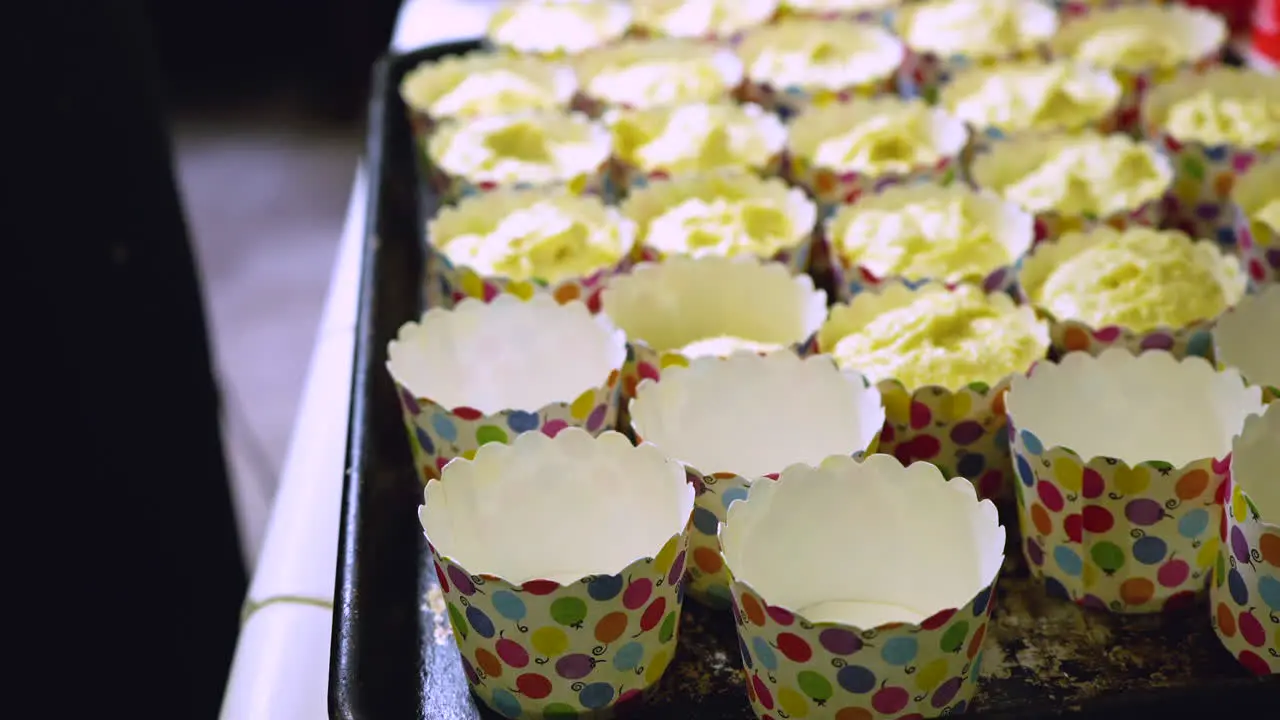 Filling cute paper cups with batter using an ice cream spoon