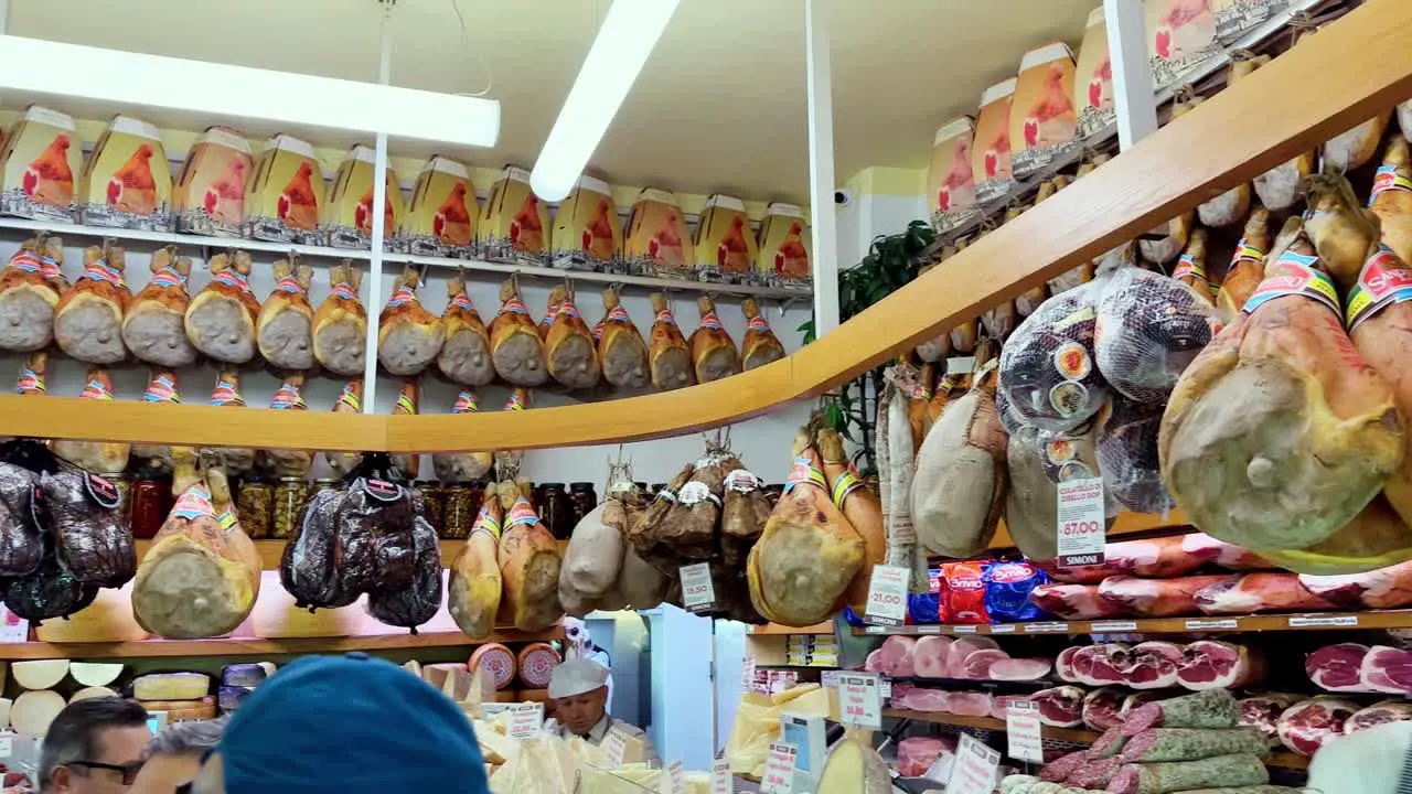 A lot of types of ham and cured meats hanging in delicatessen shop in italy