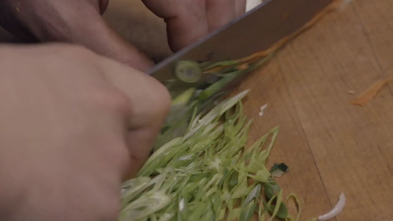 Close-up of a cook slicing scallions in a kitchen of a restaurant