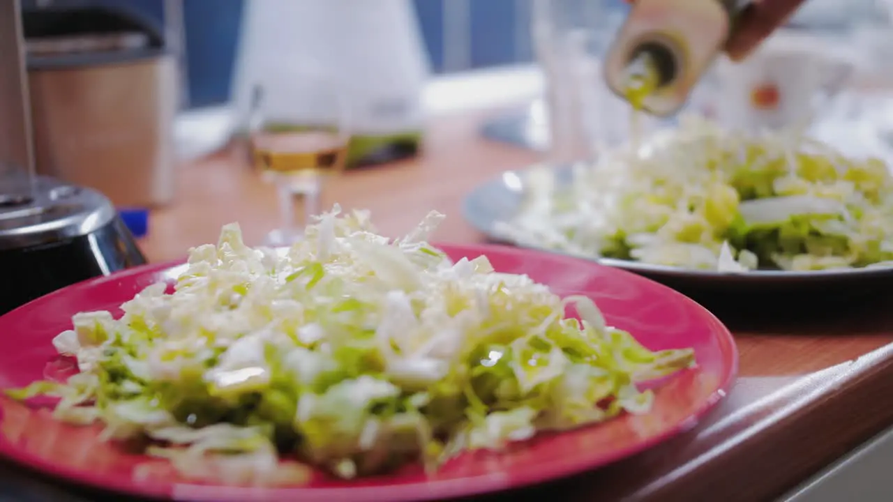 Pouring olive oil over healthy salad on red plate parallax shot