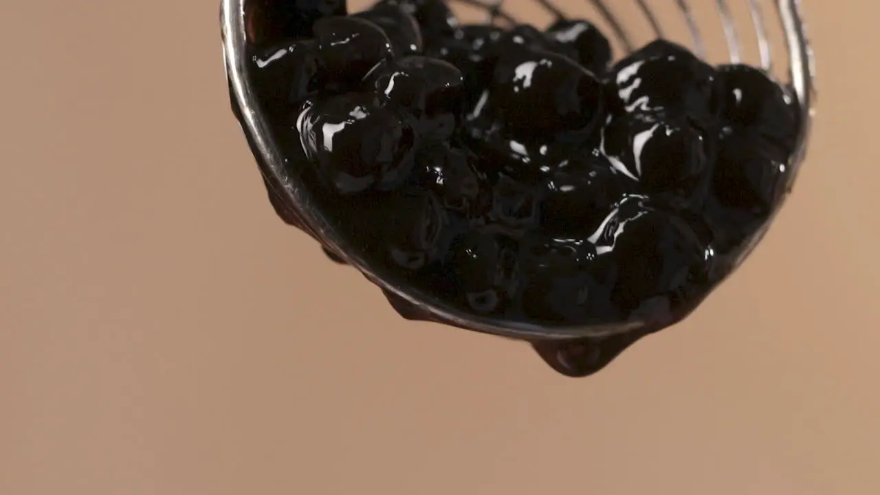  Succulent Black Tapioca Pearls Falling from Steel Skimmer Macro Shot