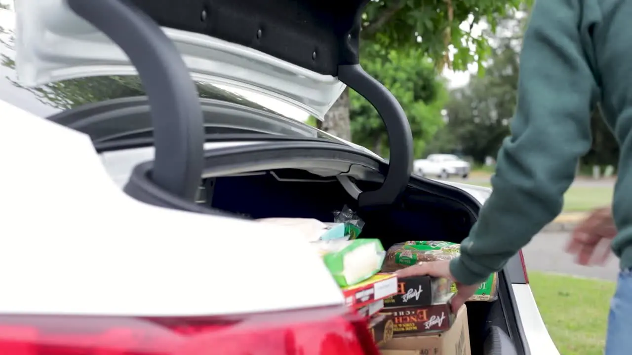 Packs Of Food In The Car Trunk For Donating To The Homeless During Covid-19 Pandemic side view slow motion