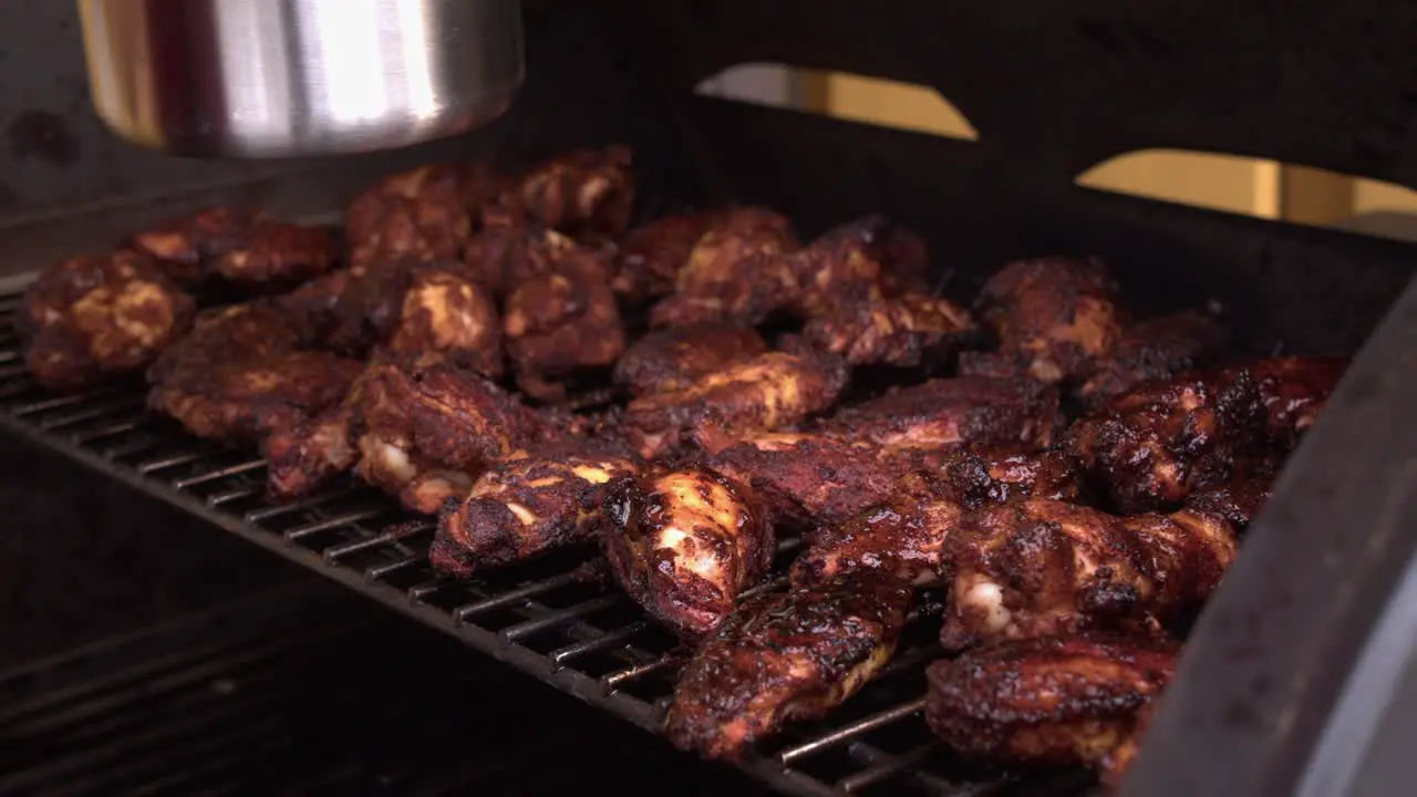 Delicious chicken wings on hot grill are basted with BBQ sauce