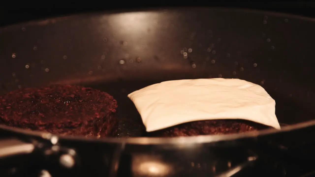 Vegan PlantBased Burgers with Cheese being Layered on Top by Hand while in Hot Pan