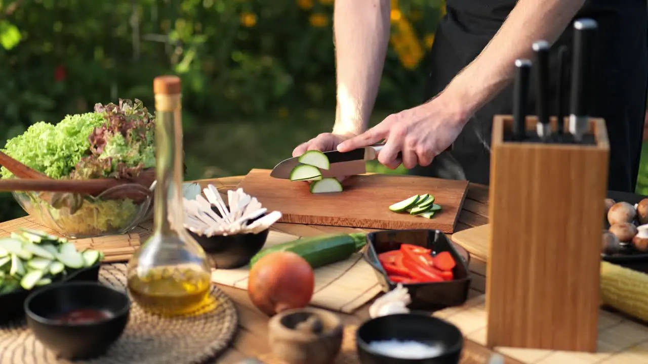 Medium shot of a male cutting zucchini into long slices in his garden