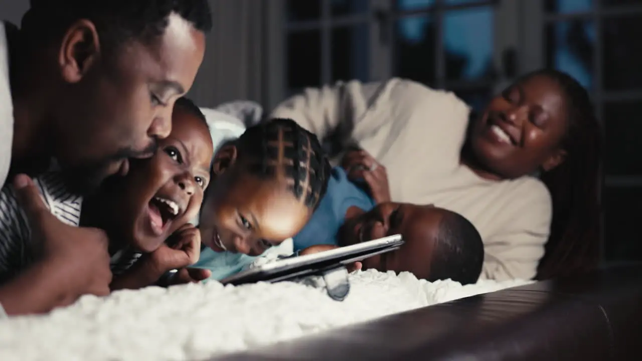 Happy night and a black family with a tablet