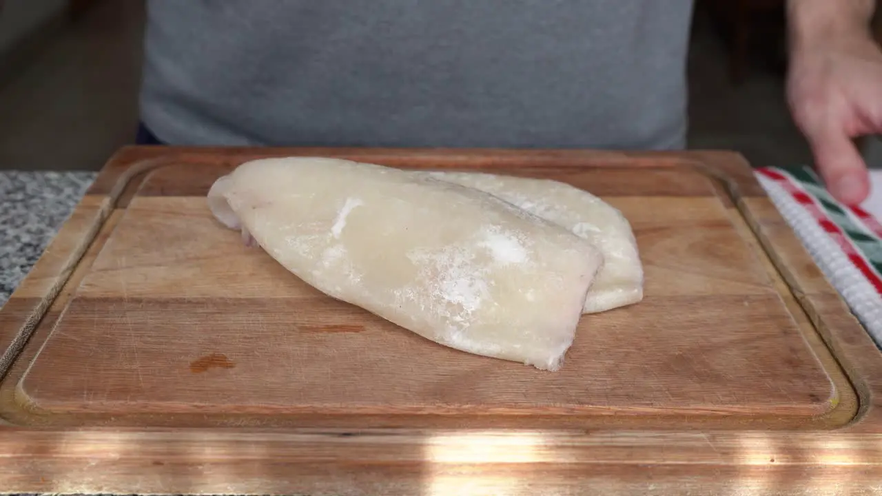 Man Places Skinless Squid On Wooden Board In The Kitchen