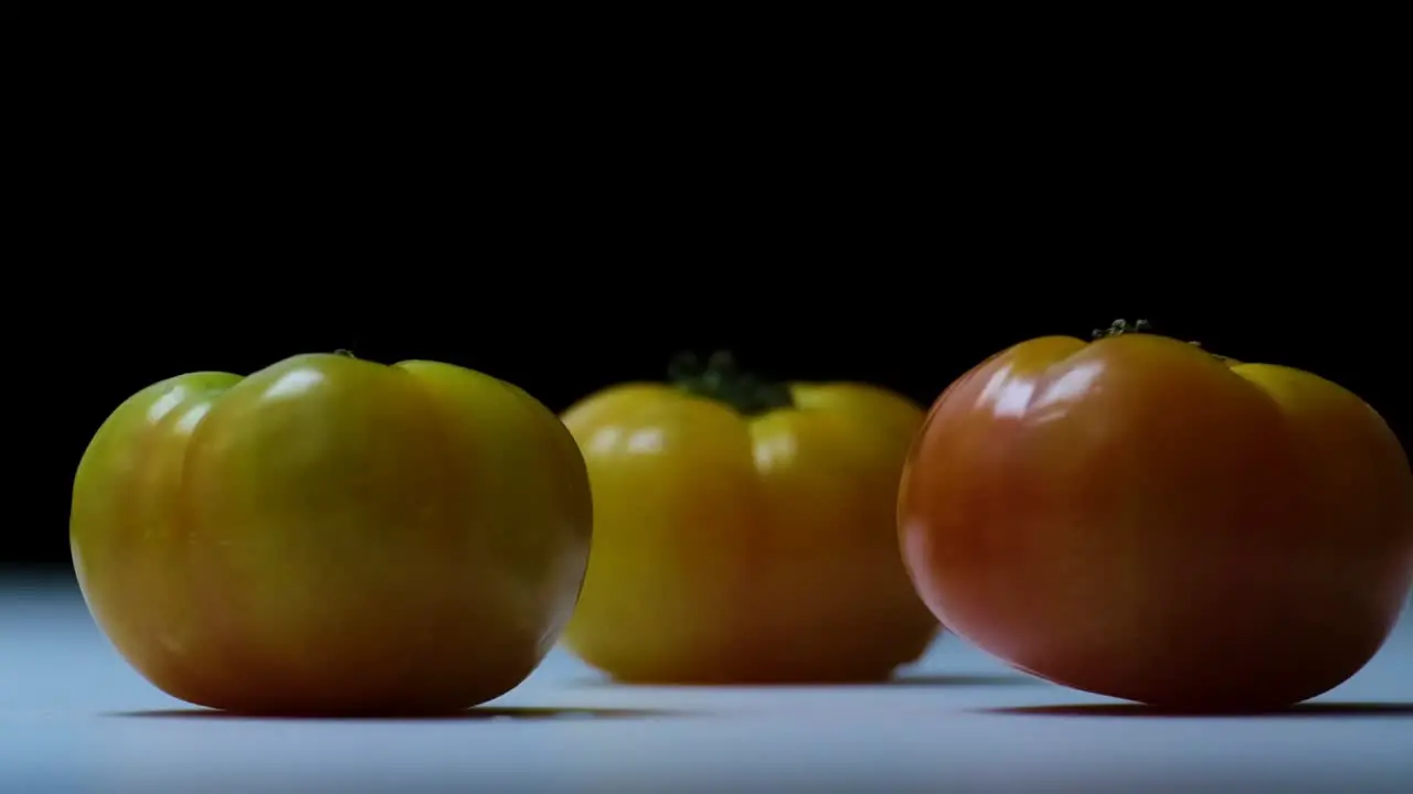 Slow Motion Shot of Two Red Roma Tomatoes Falling and Bouncing on Three Yellow Tasteful Tomatoes on a White Surface