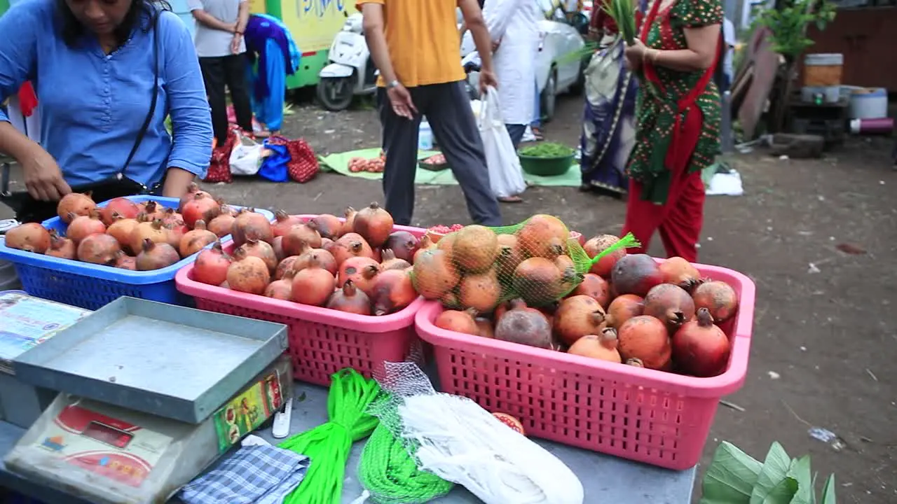 young Indian woman buying fresh Pomegranate on best local fruit market vender collect money for Pomegranate selling