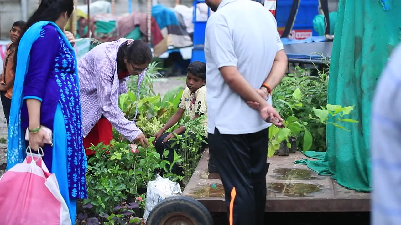 two Indian women asking price for different plants following a shot of the market to people buying a plant