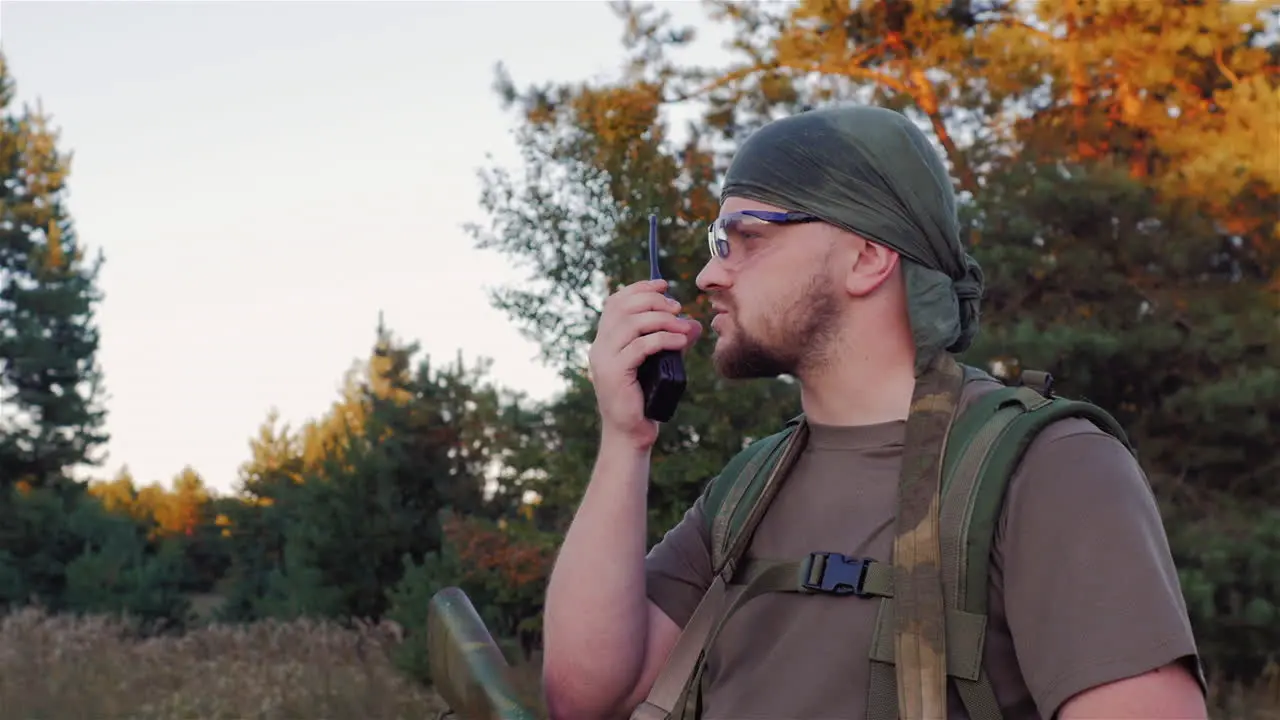 Man In Camouflage With Guns Speaking On The Radio