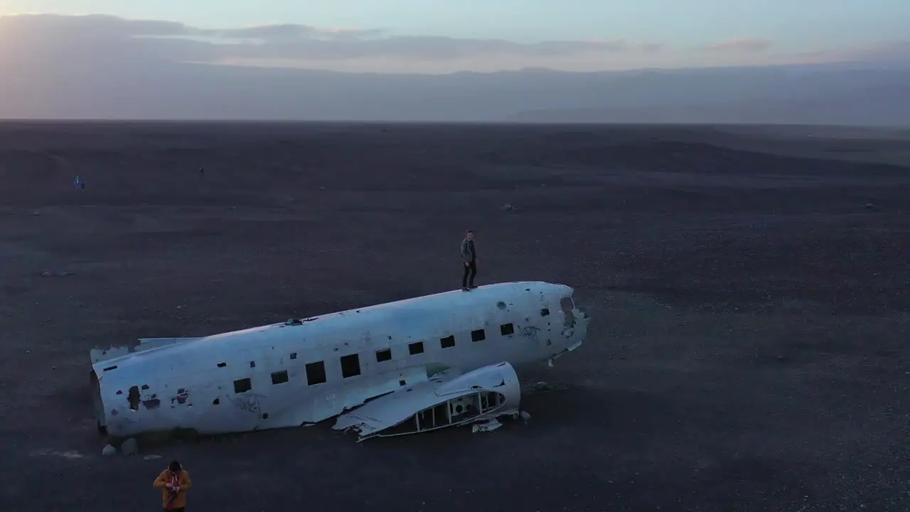 Aerial man standing on a crashed US Navy DC-3 on the black sands of Solheimasandur Iceland 1