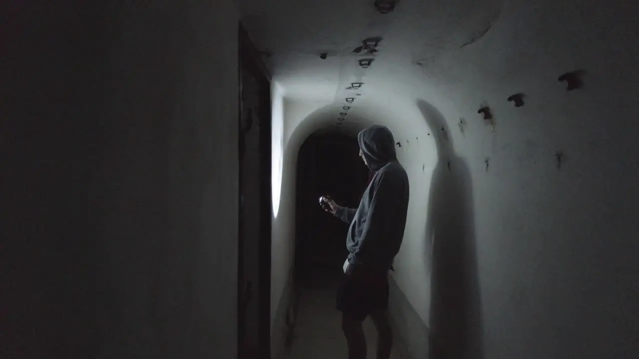 Close view of a man with a flashlight exploring the interiors of concrete military bunkers remnants from the communist-era in Albania