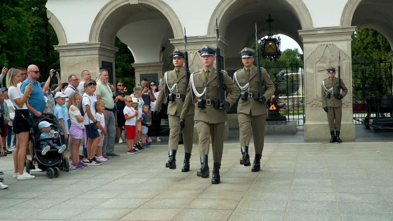 Uniformed guards in a ceremonial Tomb of the Unknown Soldier march past the eternal flame at a Warsaw memorial Piłsudski Square