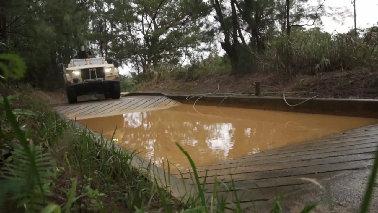 Slow Motion Of A Us Marine Joint Light Tactical Vehicle Plowing Through A Muddy Water Hazard On Okinawa Japan