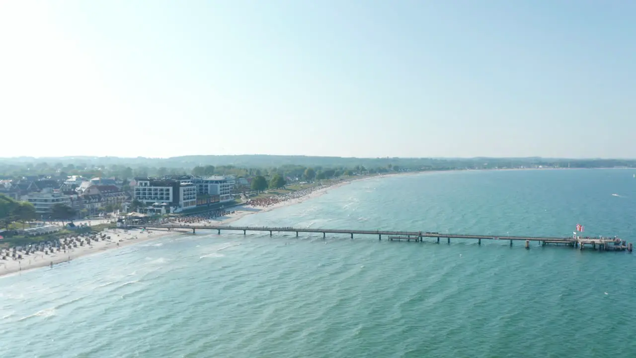 Aerial drone view flying above Baltic sea pier beach in Scharbeutz Germany summer sunny day circle pan