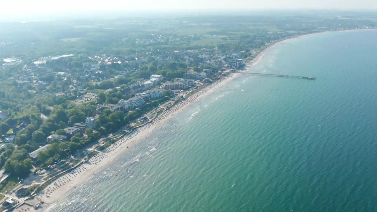 Baltic sea aerial drone view tourist beach summertime destination in Scharbeutz Germany tilt down to coast day