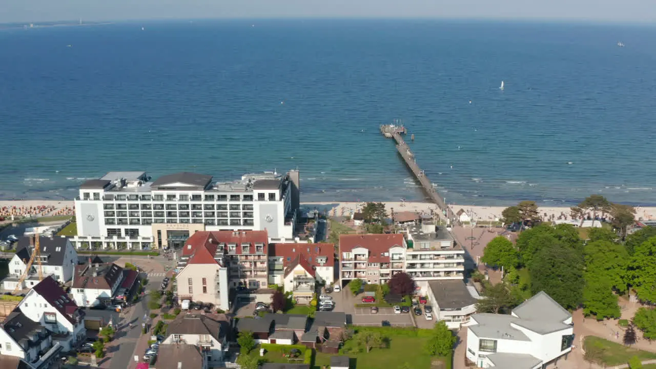 Aerial view flying above buildings facing Baltic sea beach coastline on summertime sunny day Scharbeutz Germany sideways