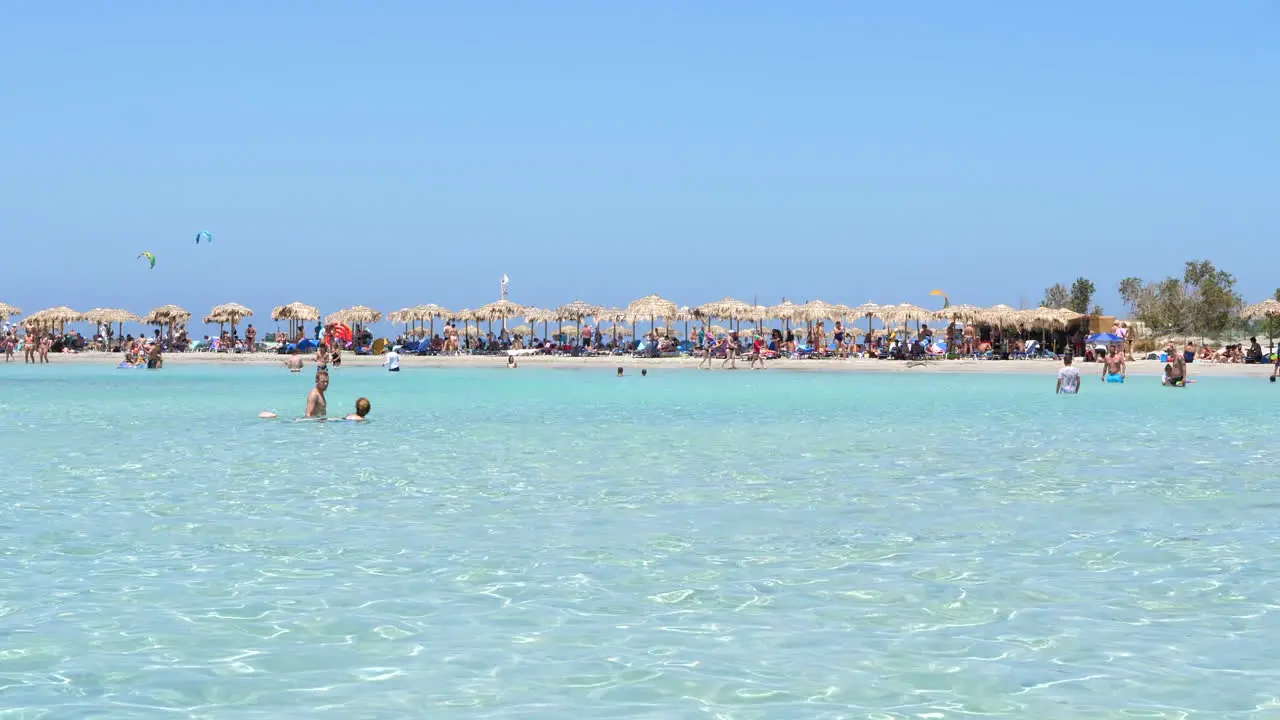 Beach packed with umbrellas and tourist in waters of Elafonissi beach Crete