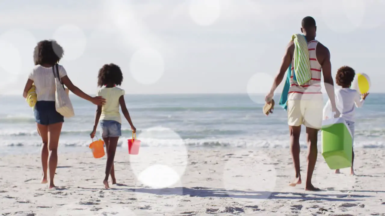 Animation of spots over african american family walking on sunny beach