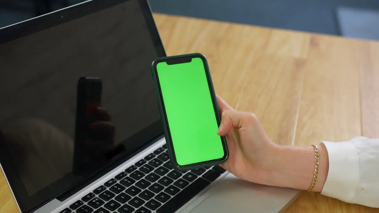 Woman using greenscreen phone in a busy office close up