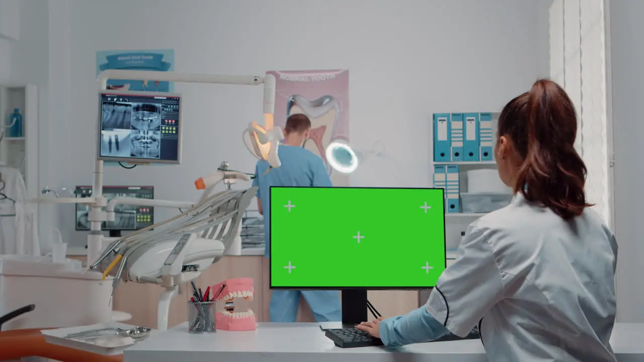 Dentist using green screen on monitor and talking to man assistant