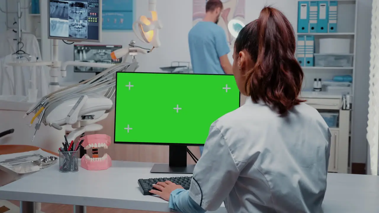 Dentist working with horizontal green screen on monitor at desk