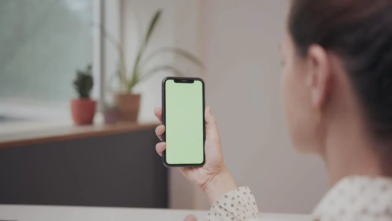 Caucasian business woman swiping on green screen smartphone while sitting at a office desk