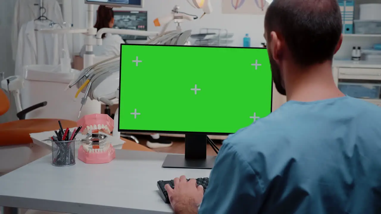 Man looking at computer with horizontal green screen