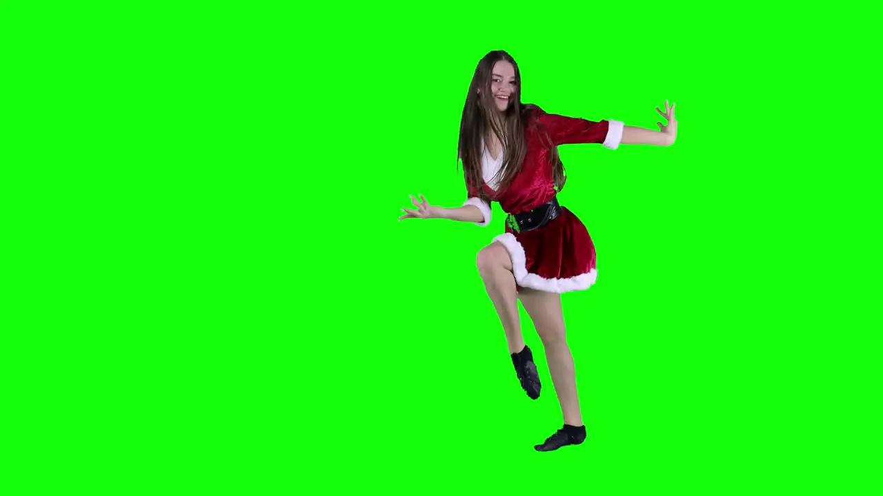 Jumping woman 20s in red Santa Christmas dress dancing spinning and dancing around having fun expressive gesticulating hands isolated on green screen background studio